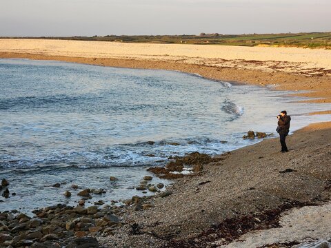 Woman takes pictures of the sea at sunset
