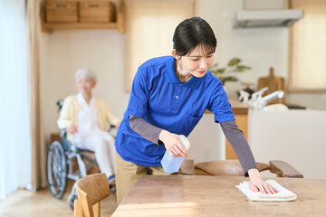 訪問介護で掃除をするアジア人介護士 © mapo