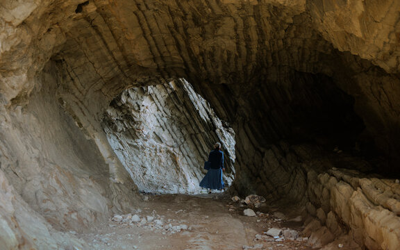 A woman quickly walking through a sea cave.