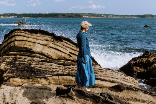 A woman resonating with nature amidst the sound of waves.