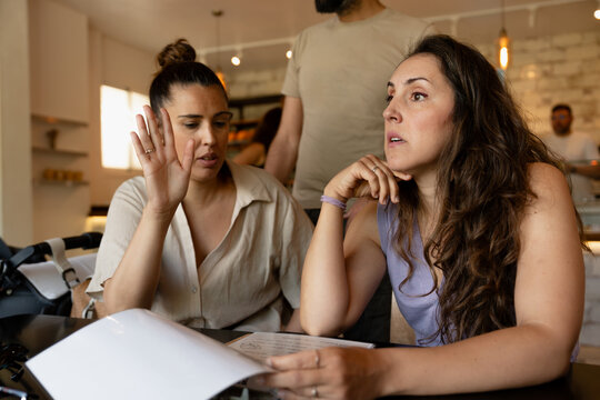 Two women discussing over menu in restaurant