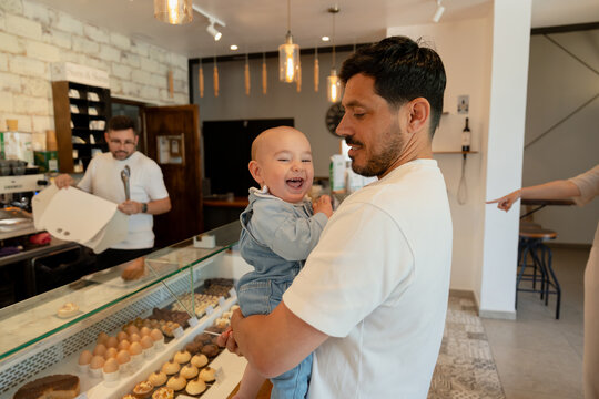 Father and baby choosing pastries in bakery