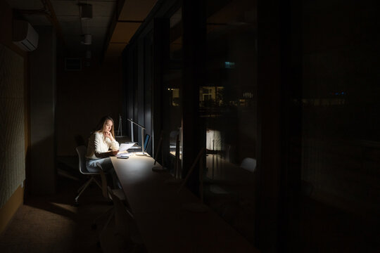 Woman Working At Office Desk at Night