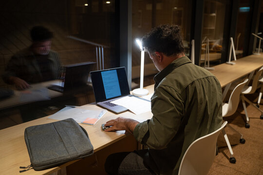 Man Working At Office Desk In Late Evening