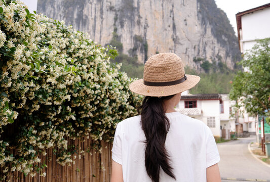 Chinese girl walking on the roadside of the wind chime jasmine wall