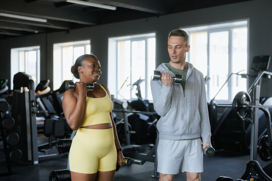 A woman works out at the gym with a trainer