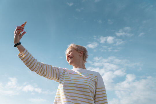 Smiling Woman Taking Selfie with Blue Sky Background