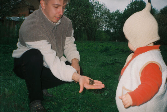Dad Showing Frog to Toddler Outdoors - film analog