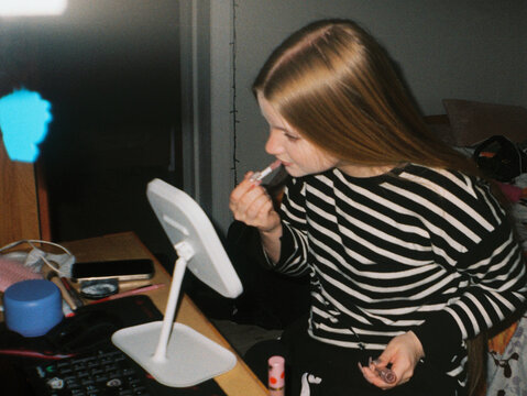 Teen Girl Applying Lip Gloss at Desk - film analog