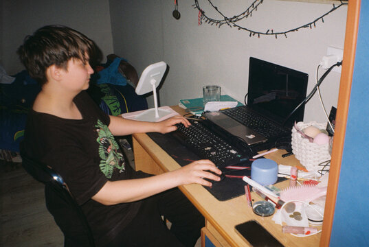 Teen Using Computer at Cluttered Desk  - film analog