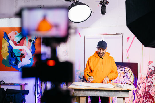 Artist drawing while camera films in a masterclass

