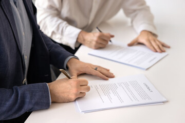 Formal commitment through contract signing. Close up view of two businessmen signing official...