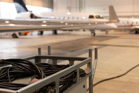 Lowangle gulfstream g engine and wing with ground cart and cable foreground, operational hangar prep for departure, power hookup and technician workflow implied