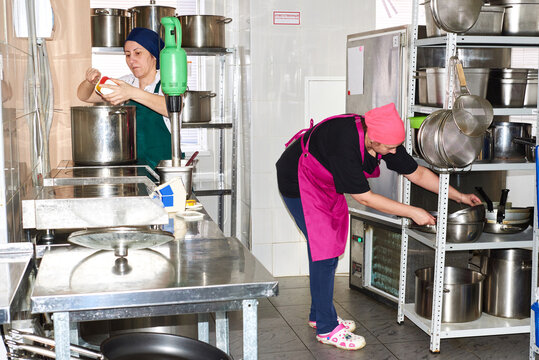 Women preparing food in a busy kitchen setting during the day
