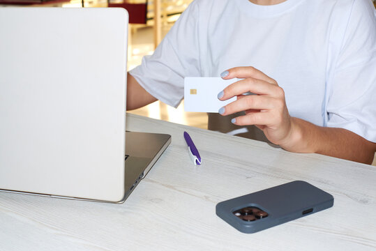 Person using a laptop and holding a credit card indoors
