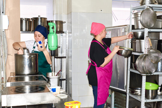 Women preparing food in a busy kitchen setting during the day