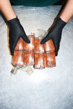Hands holding packaged frozen soups on stainless steel surface