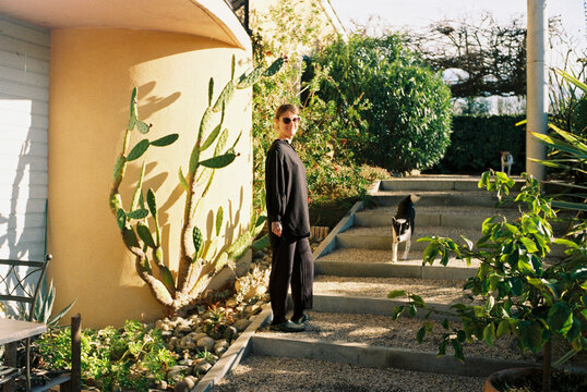 Woman Standing in Garden With Plants and Cats in Sunny Setting