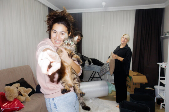 young woman holding cat in her hands and they both looking at camera