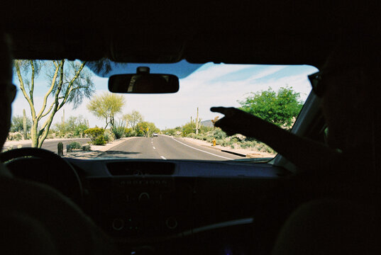 Man points out the window of a car traveling through Scottsdale, AZ