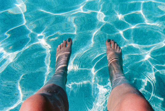 Woman soaks feet in swimming pool 