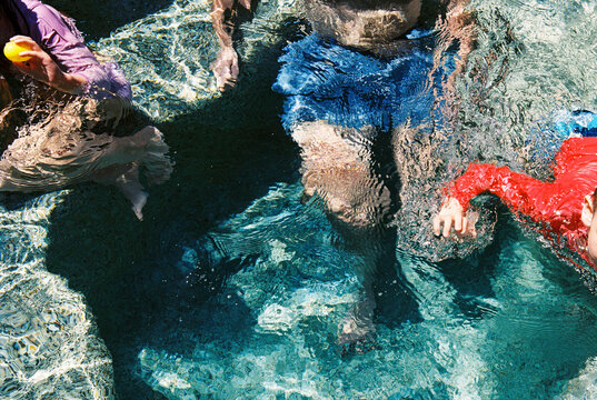 Abstract film photo of family swimming in backyard pool