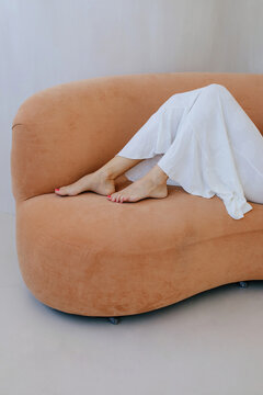 Crop woman leg with pedicure on sofa