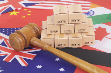 Many cardboard boxes on different national flags and judge gavel. Global trading, laws and tariffs concept.
