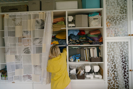 Woman seamstress choosing fabric in closet