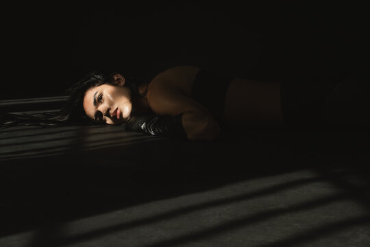 Nonbinary model lying on floor in black outfit