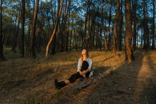 Woman Relaxing in a Tranquil Forest at Sunset in Autumn