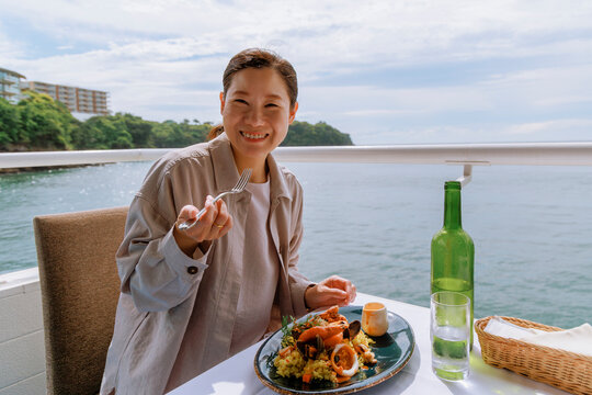 A woman enjoying seafood on a seaside terrace.