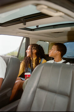 Young Friends Enjoying a Road Trip in the Backseat of a Car