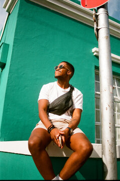 Young Man Sitting Against a Green Wall
