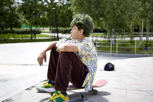 Skateboarder relaxing at a park in summer with a vibrant shirt