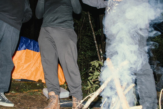 Camping at night with friends by the warm campfire under the stars