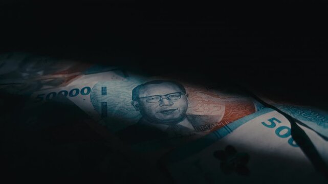 Top down rotating view of Indonesian 50,000 Rupiah banknotes under dramatic spotlight on dark background