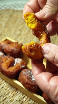 Person taking a pumpkin fritter, Bu&ntilde;uelo de Calabaza, a traditional dessert from Valencia (Spain)