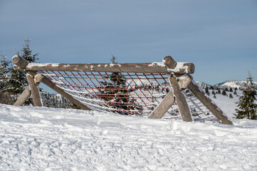 Wooden playground structure with ropes for climbing for children on top of Nova Hola in wintertime © Stefan