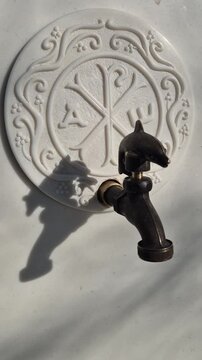 Fountain faucet marble close up of an ornate dolphin handle bronze faucet on a carved white marble wall with traditional architectural detail