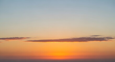 Obraz premium Vibrant orange and blue gradient sunset sky with clouds.