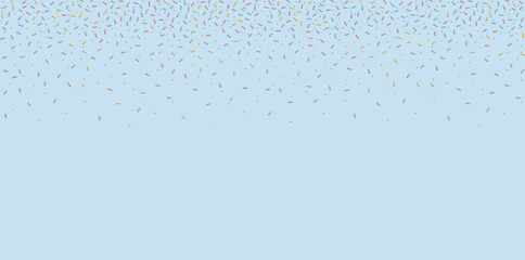 Soft pastel confetti sprinkles scattered on light blue background