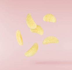 Fototapeta premium Levitating peeled segments of sweetie fruit or oroblanco on a pink background. Fresh juicy citrus slices flying in the air.