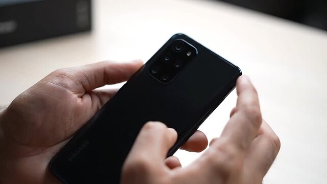 Hands holding a modern black smartphone with multiple cameras