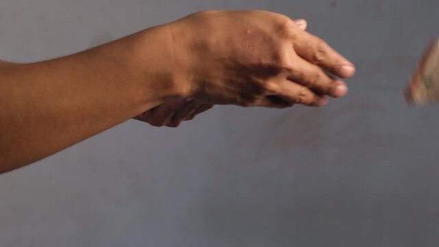 Close up footage of a hand holding rupiah money while making a transaction and giving it to the other hand as the recipient