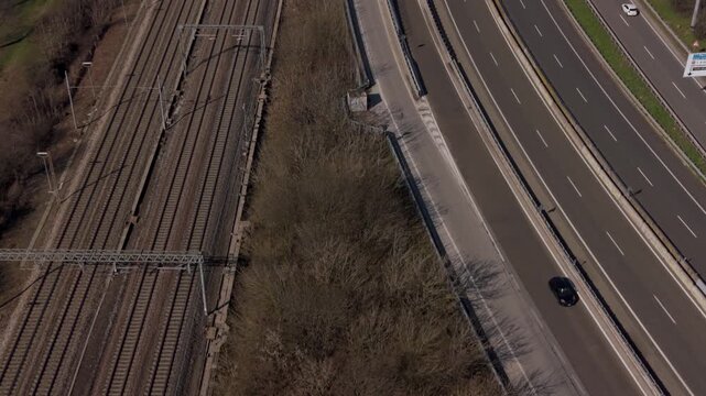 Aerial View of Highway and Train Tracks: An aerial perspective showcases the convergence of a multi-lane highway and parallel train tracks, illustrating modern transportation infrastructure.