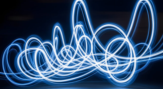 Vibrant blue swirling light trails dance across a dark blurred background with a soft haze and dreamlike quality from a close-up viewpoint