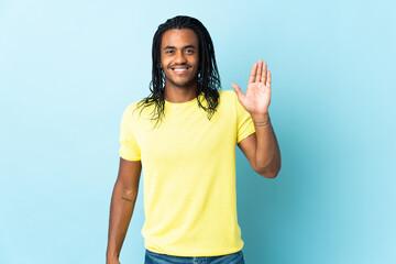 Delivery African American man with braids isolated on white background saluting with hand with happy expression © luismolinero