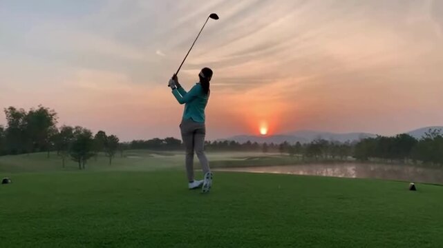 A golfer swinging a club during sunset on the golf course
