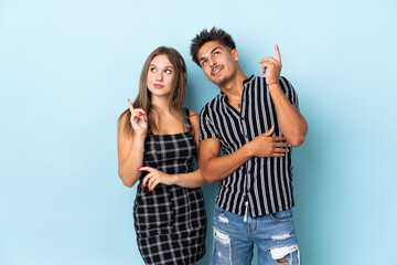 Naklejka premium Teenager caucasian couple isolated on blue background pointing a great idea and looking up